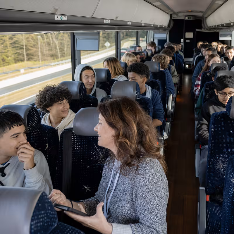 Group boarding a white charter bus for School Transportation transportation in Los Angeles